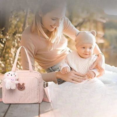 Sac-à-langer-rose-sur-un-banc-de-parc-avec-bébé-et-maman