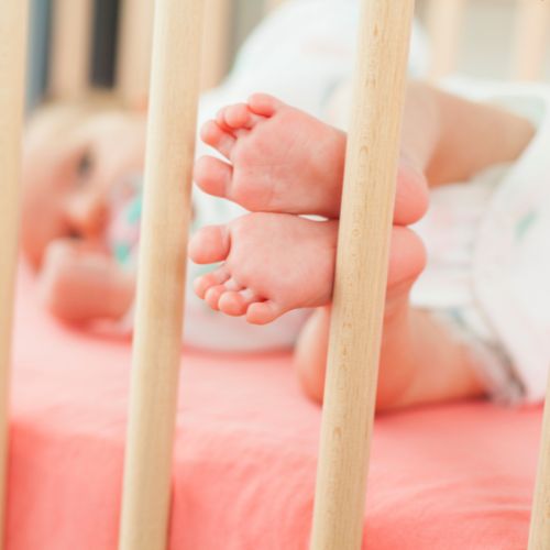 pieds de bébé appuyés contre les barreaux du lit