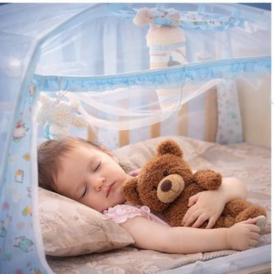 petite fille dort avec son ourson dans son lit moustiquaire