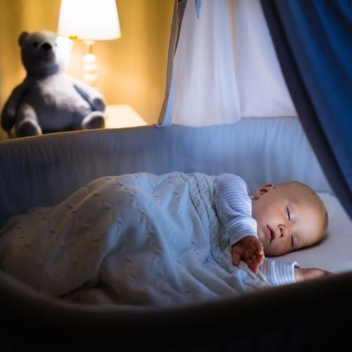 bébé dort dans son berceau sous son ciel de lit