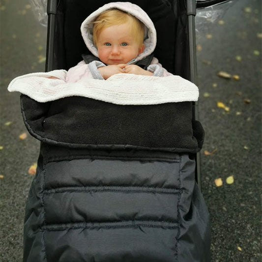 Bébé dans sa poussette bien au chaud dans chancelière noir