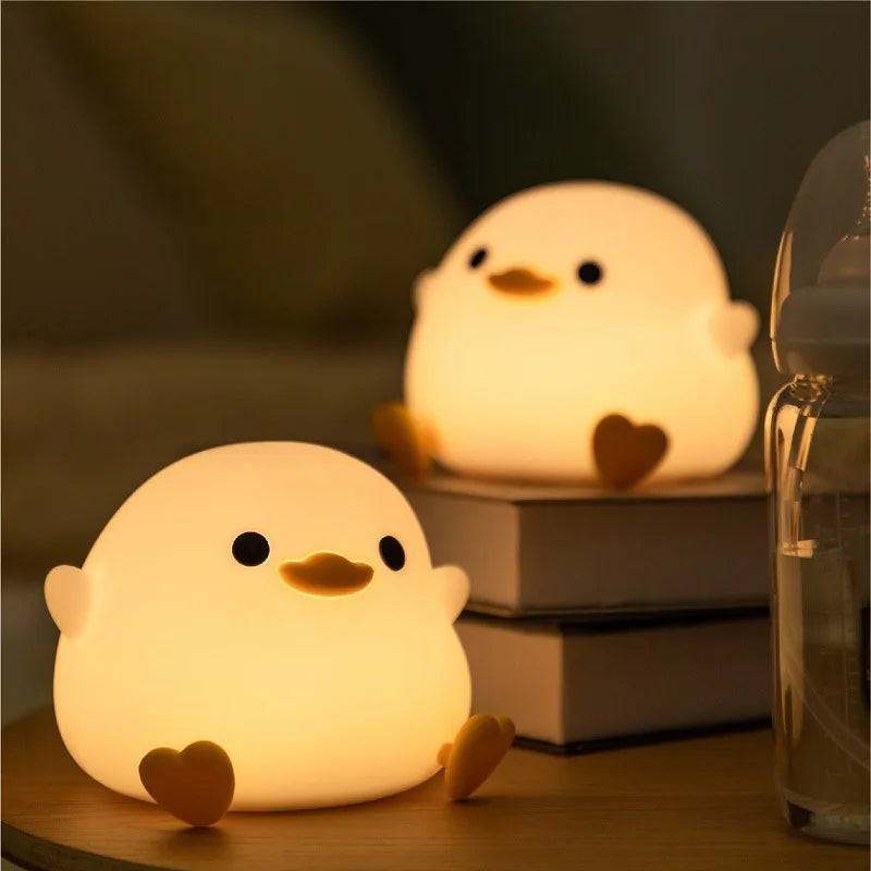 Veilleuse-silicone-baby-duck -allumé-assis-sur-table-de-chevet