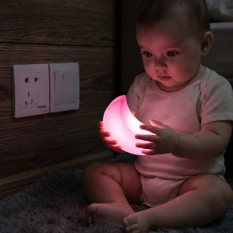 Alice tient dans ses mains la veilleuse murale bebe lune rose