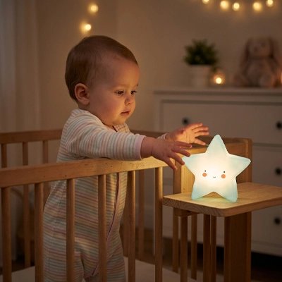 Bébé debout dans son berceau attrape la veilleuse etoile bebe