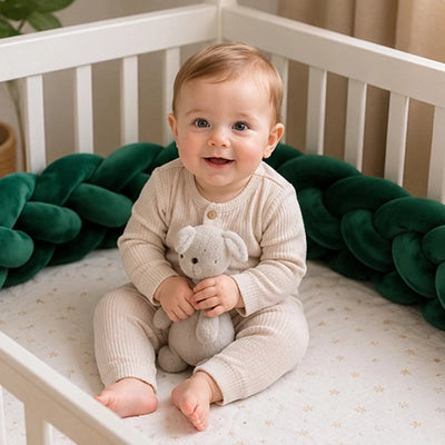Bébé assis dans son berceau avec doudou et tour de lit tresse vert