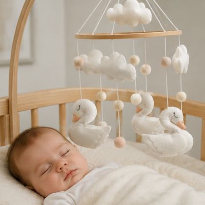 Bébé dort paisiblement en dessous de son mobile lit bebe cygne blanc