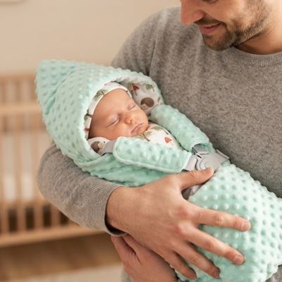 Nouveau-né dans son nid dAnge siege auto dans bras papa