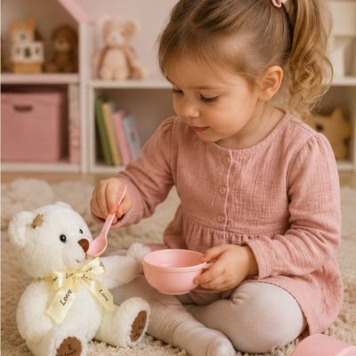 Ours-peluche-blanc-et-fille-qui-joue-a-le-nourrir