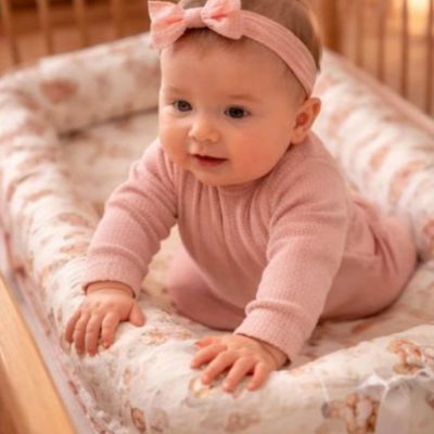 bébé essaie de passer au-dessus des rebords du réducteur de lit cododo