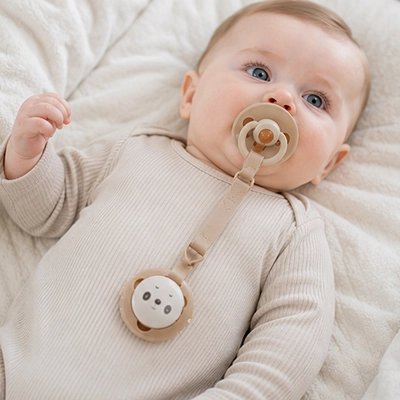 bébé couché avec son accroche tétine beige