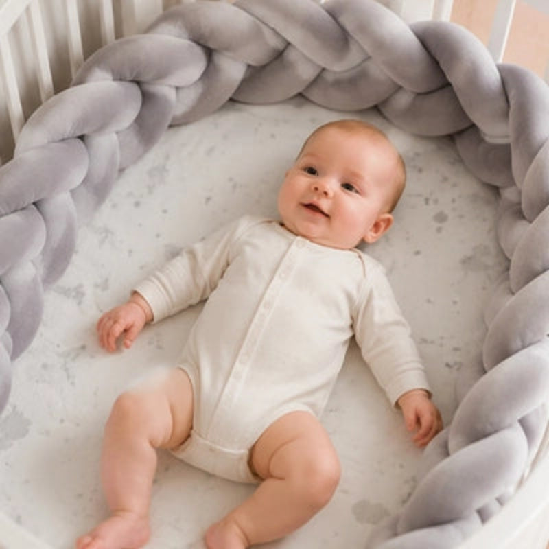 bébé dans berceau souriant entouré  tresse de lit bébé grise