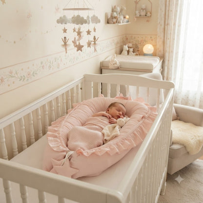 Bébé dort dans son reducteur de lit rose dans le berceau.