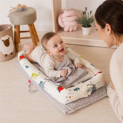 Bébé à plat ventre dans son réducteur de lit sourit maman