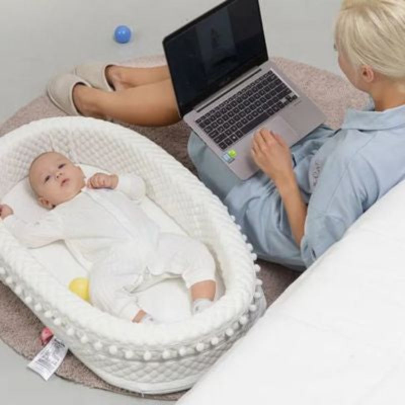 bébé dans son reducteur cododo au sol avec maman travail ordinateur