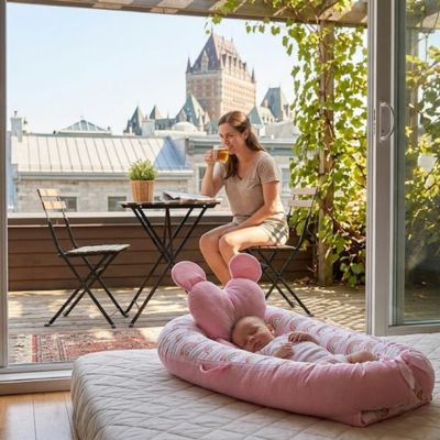 Bébé dort dans son réducteur pendant que maman boit son café sur la terrasse.