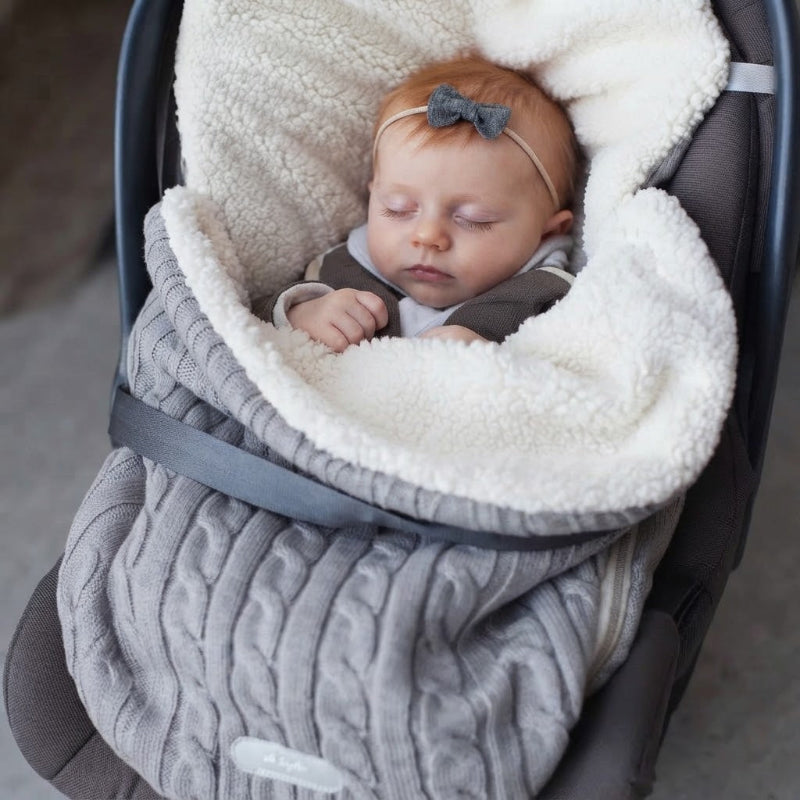 Bébé dort dans son siège d'auto dans son nid d'ange cosy