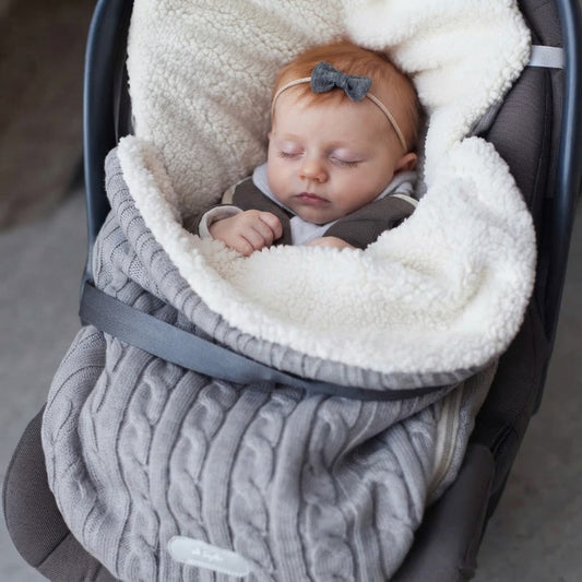 Bébé dort dans son siège d'auto dans son nid d'ange cosy