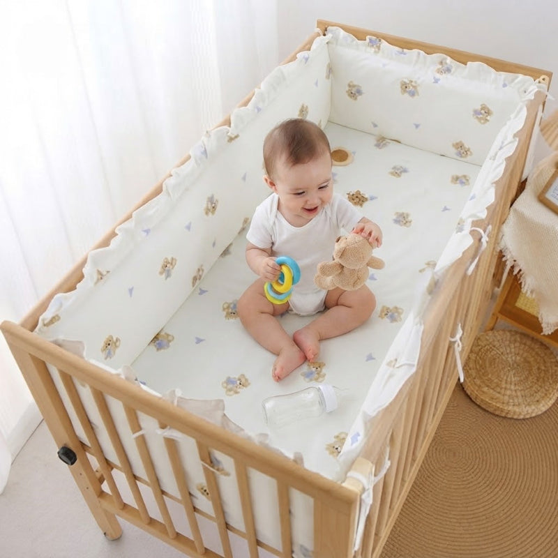 bébé qui s'amuse dans berceau protégé par tour de lit ourson