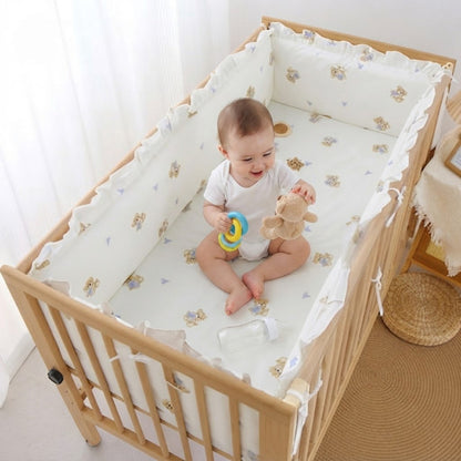 bébé qui s'amuse dans berceau protégé par tour de lit ourson