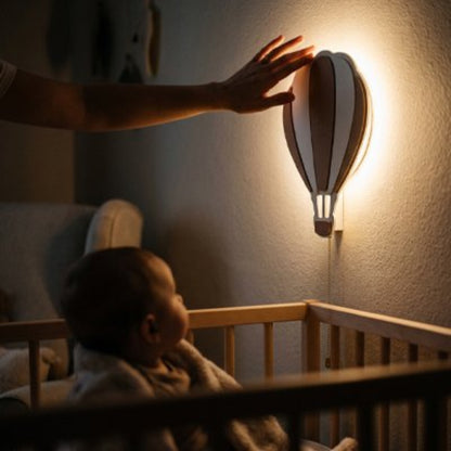 Bébé regarde la veilleuse murale montgolfière.