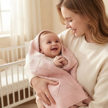 Bébé sourit à maman dans sa couverture bebe tricot