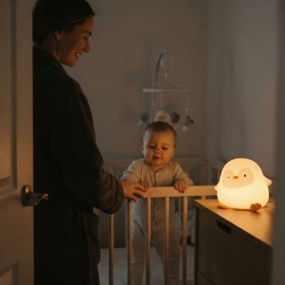 Maman dans la chambre de bébé la nuit avec veilleuse LED allumée.