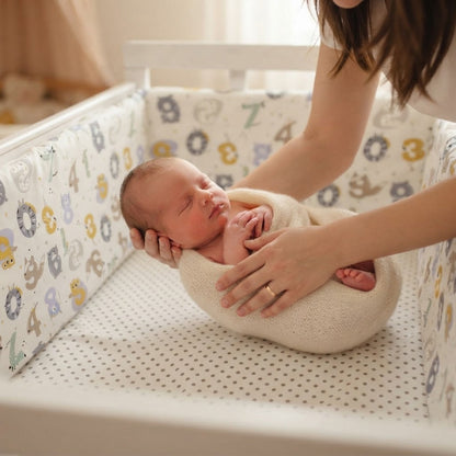 Maman dépose bébé dans le berceau avec tour de lit bebe