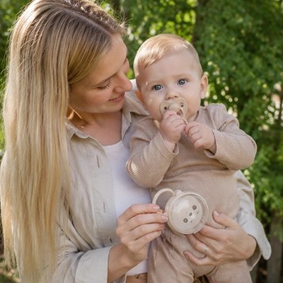 Maman et bébé dehors avec porte tetine beige