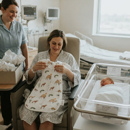 Maman maternité reçoit tog gigoteuse à côté bébé.