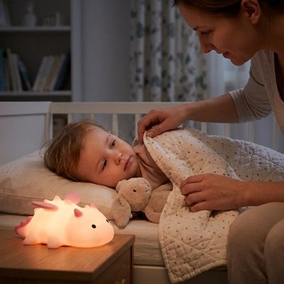 maman qui borde sa fille accompagnée de veilleuse dragon rose