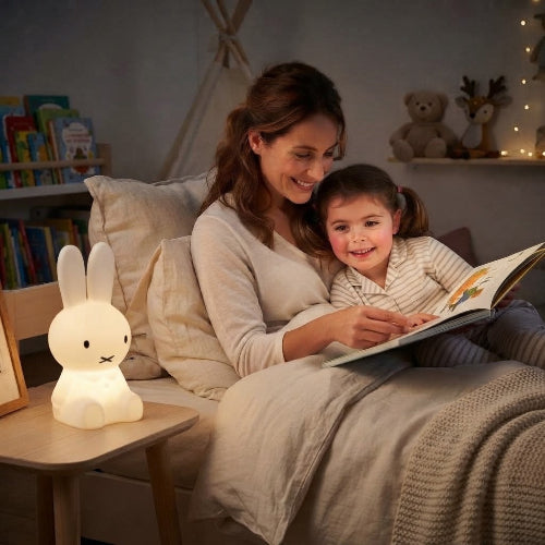 Maman raconte une histoire à Léa avec la veilleuse lapin sur bureau