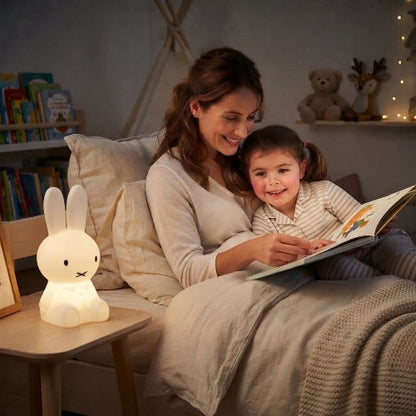 Maman raconte une histoire à Léa avec la veilleuse lapin sur bureau