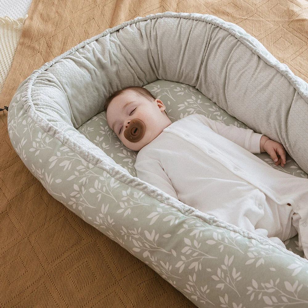 réducteur-de-lit-bébé- herbe-et-bébé-dort