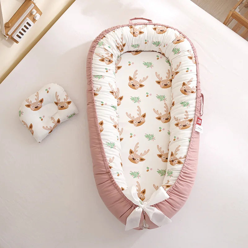 reducteur-de-lit-bebe-rose-avec-motif-de-tête-de-cerf et-son-petit-oreiller-déposer-à-coté