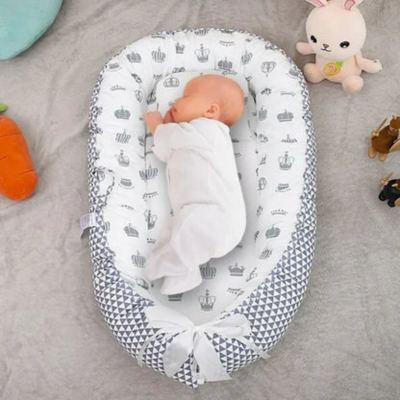 reducteur-de-lit-bebe- motifs-couronne-royal-avec-un-bébé-en-pyjama-blanc-qui-dors-