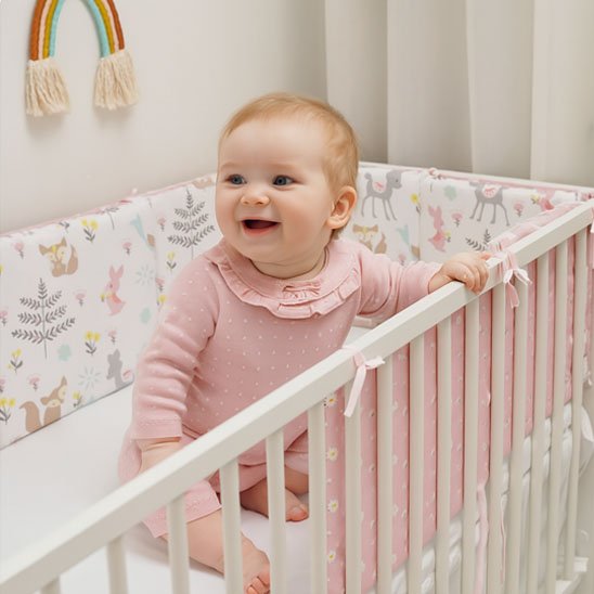 Tour de lit pour bebe fille dans son berceau souriante