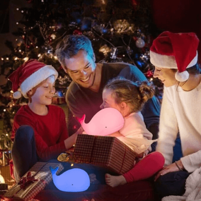   Petite-fille avec ses parents et son frère qui reçoit la veilleuse baleine en cadeau de Noël